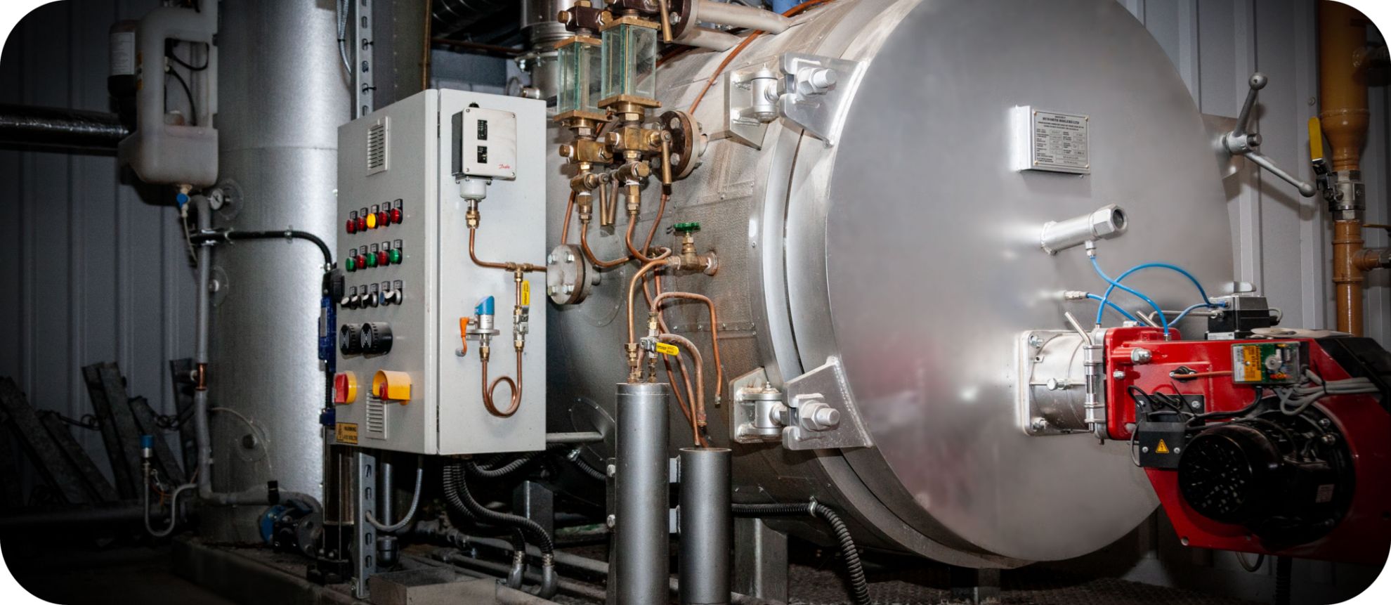 Skid mounted industrial boilers with control panel, gauge glasses and a red burner